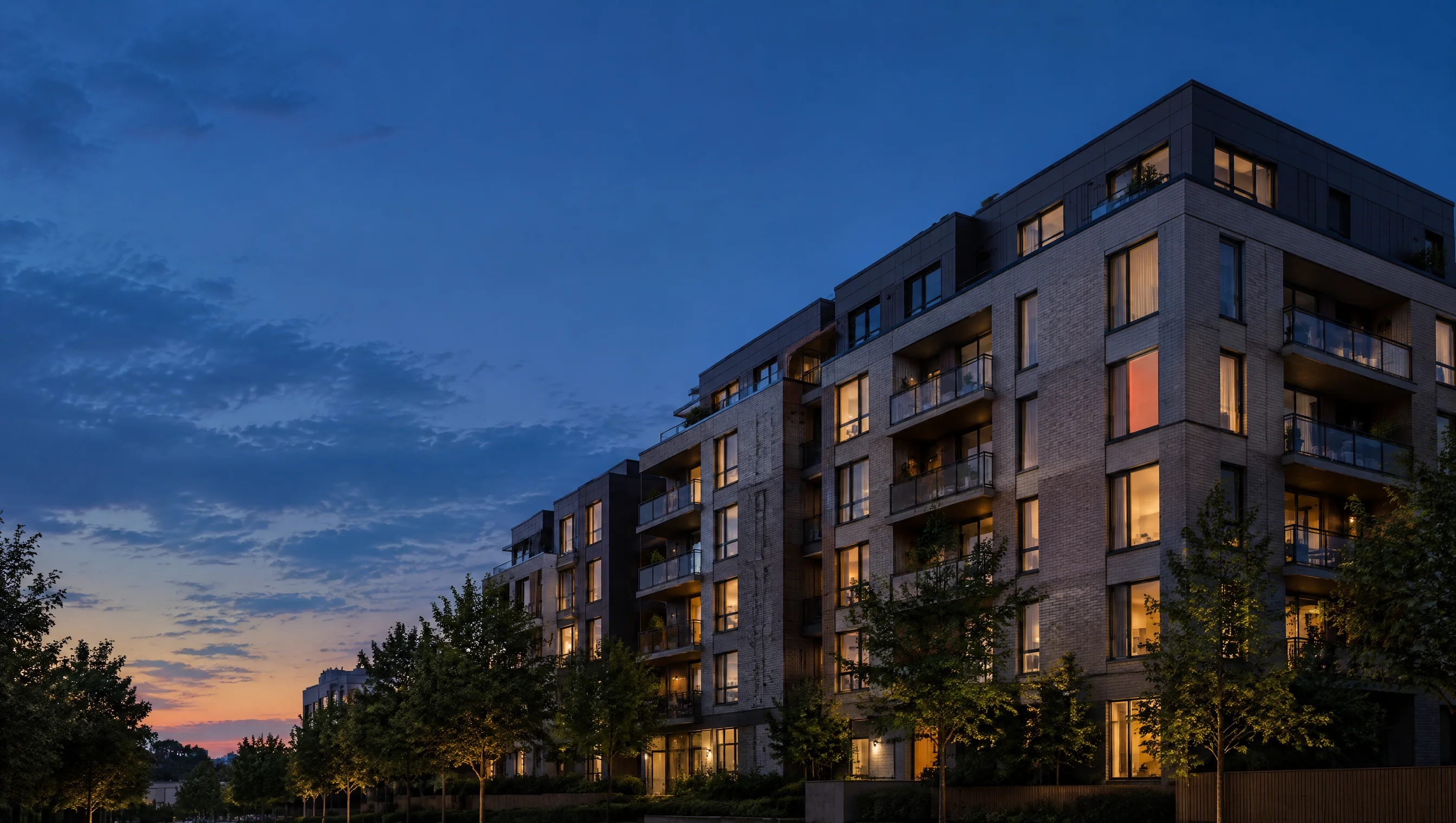 Illustrative apartment building at dusk with warmly lit windows.